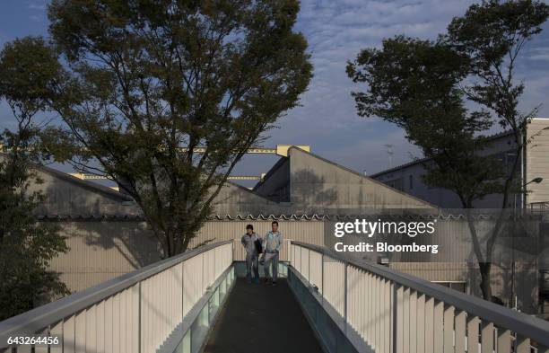 Workers walk along a pedestrian overpass outside the Toyota Motor Corp. Motomachi plant in Toyota City, Aichi, Japan, on Friday, Oct. 14, 2016....