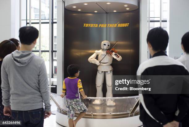 Visitors look at a Toyota Motor Corp. Partner Robot playing a violin in the showroom at the company's headquarters in Toyota City, Aichi, Japan, on...