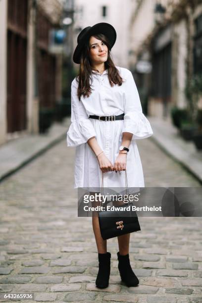 Sarah Benziane, fashion and life style blogger, wears a Newlook white dress, a The Kooples belt, a black hat, Newlook black shoes, a Christian...