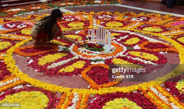Bangladeshi woman decorates the Bangladesh Central Language Martyrs' Memorial monument with flowers in homage to the martyrs of the 1952 Bengali...