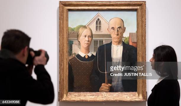 Gallery assistant poses alongside an artwork entitled "American Gothic" by US painter Grant Wood, during a photocall to promote the forthcmoing...