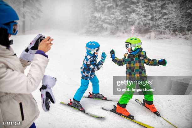 kids and mother having fun skiing together on winter day - ski high five stock pictures, royalty-free photos & images