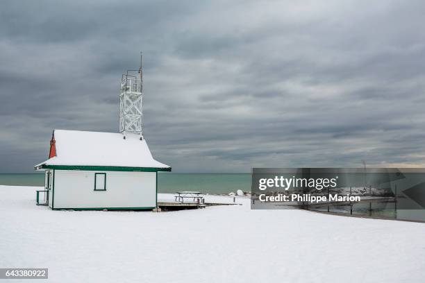 after depositing a fresh blanket of snow, winter storm clouds pass overhead of leuty lifeguard station - woodbine and kew beach, toronto - kew cottages stock pictures, royalty-free photos & images