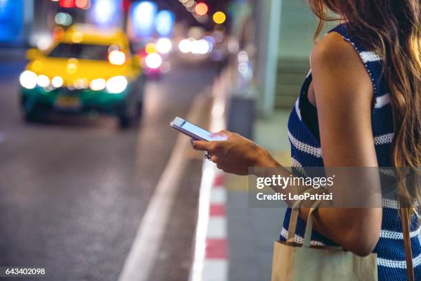 nacht in bangkok - frau warten auf ein taxi - taxi fahrgemeinschaft stock-fotos und bilder