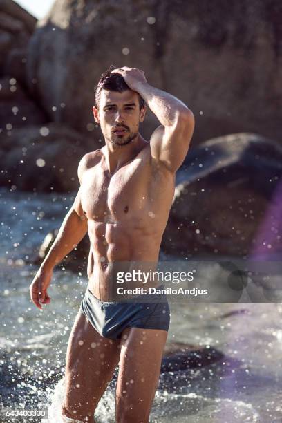 posrtrait of a handsome ripped young man - hunky guy on beach stock pictures, royalty-free photos & images