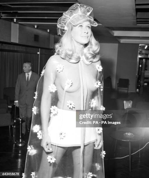 Aldine Honey models a Berkertex flower-patterned plastic rain cape worn over a mini skirt at a show of Spring fashions in London.