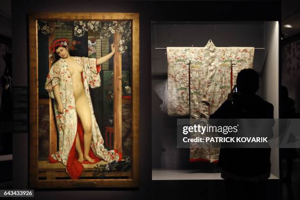 Person takes a picture of a kimono next to a painting by late artist James Tissot "La japonaise au bain" during the inauguration of the exhibition...