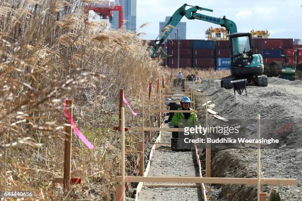Construction workers are seen next to an excavator at the site of Japan's first large scale casino resort at Yumeshima Island on February 21 in...