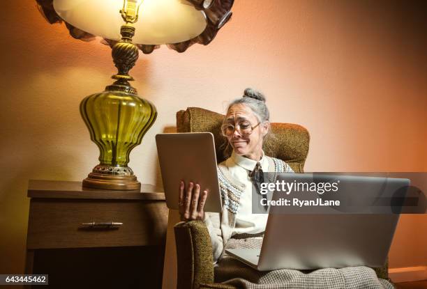 grandma using multiple modern electronics - granny chair stock pictures, royalty-free photos & images