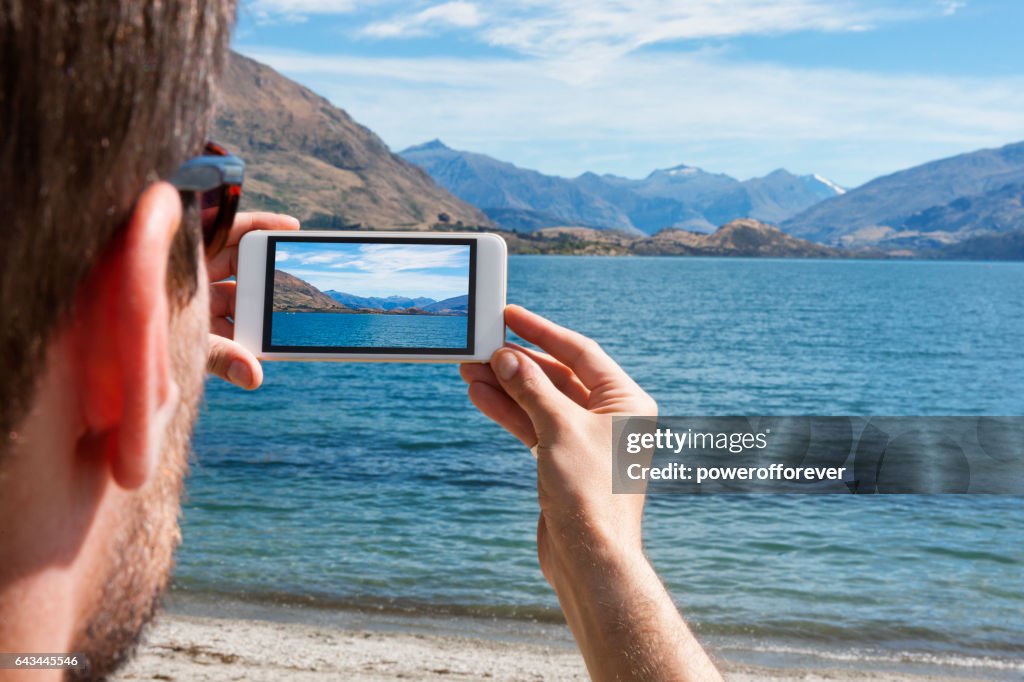 Tourist taking photo at Lake Wanaka in the Southern Alps of New Zealand