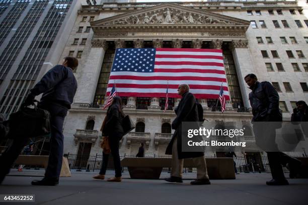 Pedestrians walk past American flags hanging outside the New York Stock Exchange in New York, U.S., on Tuesday, Feb. 21, 2017. U.S. Stocks rose to...