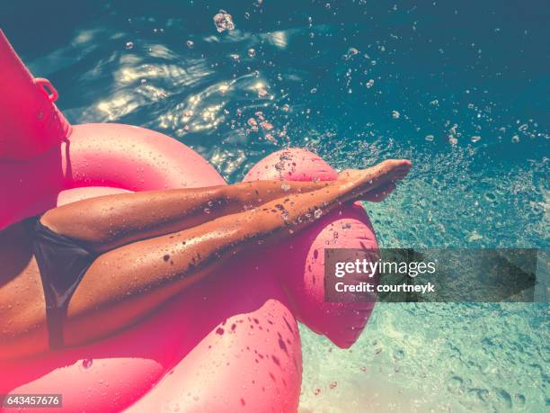 donna che galleggia su un gonfiabile rosa in piscina. - girl liquid foto e immagini stock