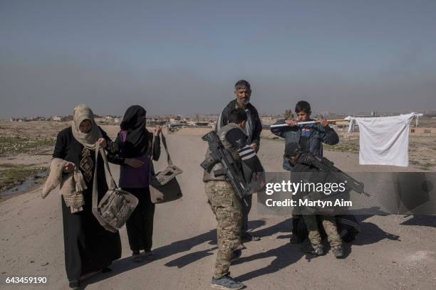 Iraqi Emergency Response Unit soldiers body check an Iraqi boy holding a white flag and his father who have fled the Islamic State held village of...