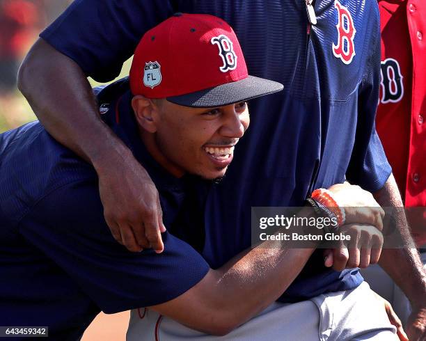 Boston Red Sox right fielder Mookie Betts shares a laugh and an embrace with Boston Red Sox outfielder Chris Young under whose arm he is pictured...