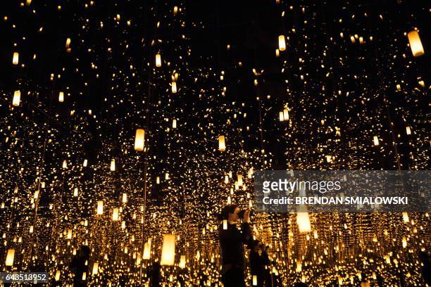 Woman photographs inside the Aftermath of Obliteration of Eternity room during a preview of the Yayoi Kusama's Infinity Mirrors exhibit at the...