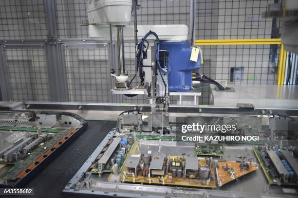 This photo taken on February 21, 2017 shows a robot removing a screw from a flatscreen television at a Panasonic recycling factory in Inashiki,...