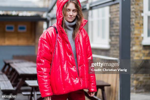 Model wearing a red flared pants, red down feather jacket and a grey knit shirt outside Marques Almeida on day 5 of the London Fashion Week February...