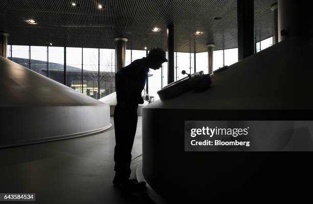 An employee checks the glass inspection door of a mash tun at the Asahi Kanagawa Brewery, operated by Asahi Breweries Ltd., a unit of Asahi Group...