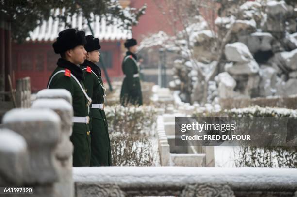 Chinese paramilitary guards stand in the snow for a visit by French Prime Minister Bernard Cazeneuve at the Forbidden City in Beijing on February 22,...