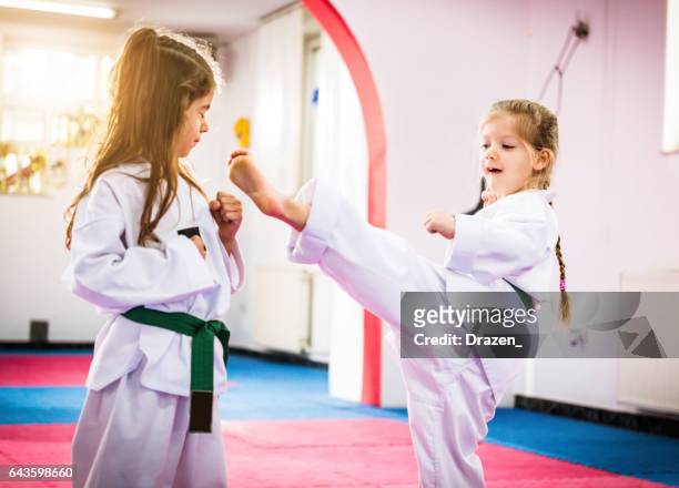 zwei süße mädchen auf taekwondo training, tretend und selbstverteidigung zu lernen - grüner gürtel sport stock-fotos und bilder