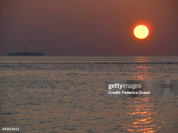 colorful maldivian sunset with fihalhohi island in the background - fihalhohi stock-fotos und bilder
