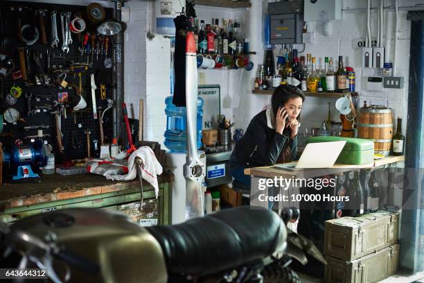 female owner in motorcycle workshop. - snapshot of britain stock-fotos und bilder