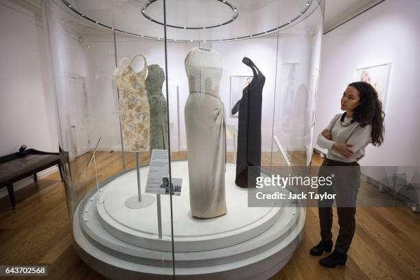 Member of staff poses beside a 1992 Catherine Walker grey silk satin dress with simulated pearl embroidery on the bodice worn by Princess Diana for a...