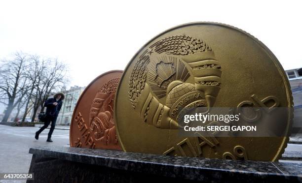 Man walks past the giant Belarusian ruble coin monument near the Ministry of taxes-and-duties in Minsk, on February 22, 2017.