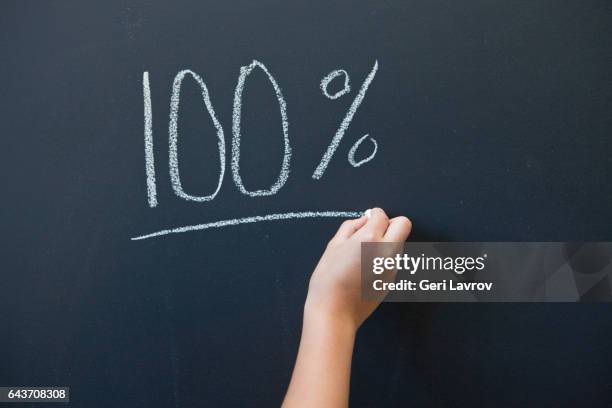 a child writing the word 100% on a blackboard - サンタイネス ストックフォトと画像