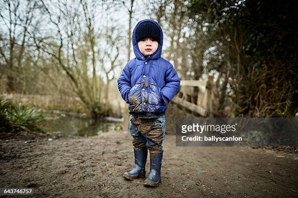 boy covered in mud in countryside. - boy jeans stockfoto's en -beelden