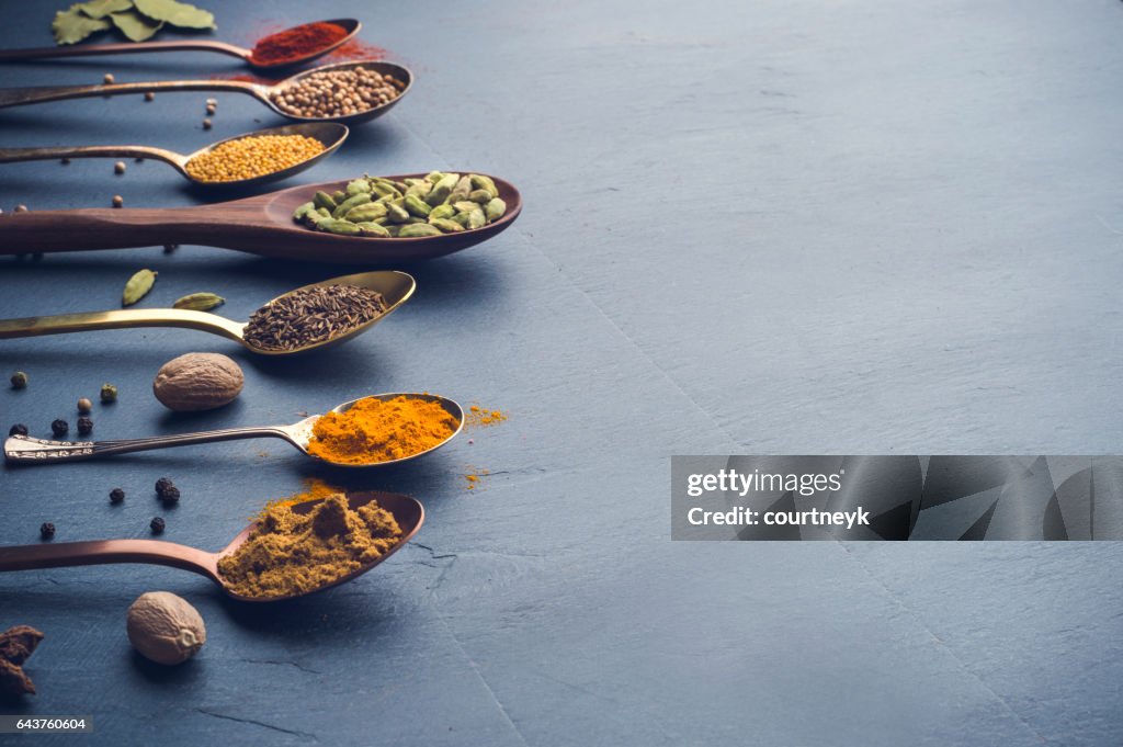 Variety of herbs and spices on slate background.