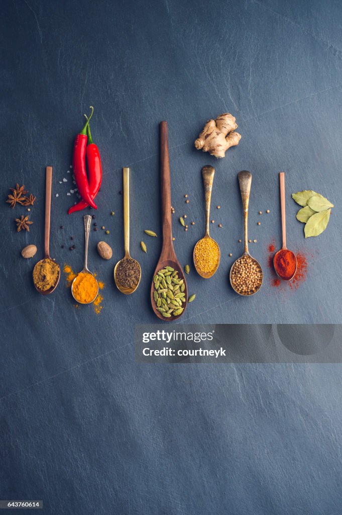 Variety of herbs and spices on slate background.