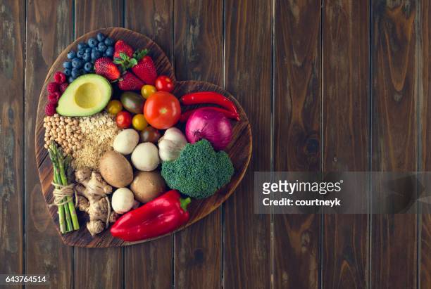 healthy food on a heart shape cutting board - food staple stock pictures, royalty-free photos & images