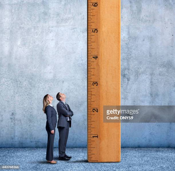 zakenman en zakenvrouw opzoeken van een lange ladder - measurement stockfoto's en -beelden
