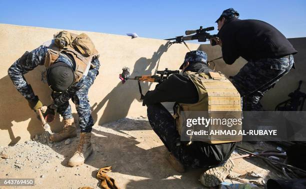 Member of the Iraqi security forces creates holes in a wall for snipers as two others take position in the village of al-Buseif, south of Mosul,...