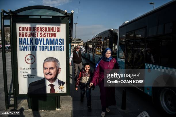 Syrian woman and a her child walk past a poster of Turkish Prime Minister Binali Yildirim for a meeting ahead of an upcoming referendum in the...