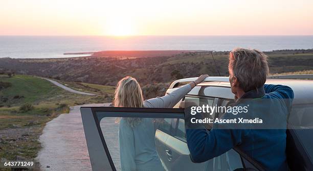 couple look down road towards sea, sunrise - two cars ストックフォトと画像