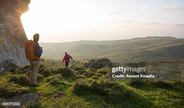 hiking couple walk across meadow towards hills - cyprus stockfoto's en -beelden