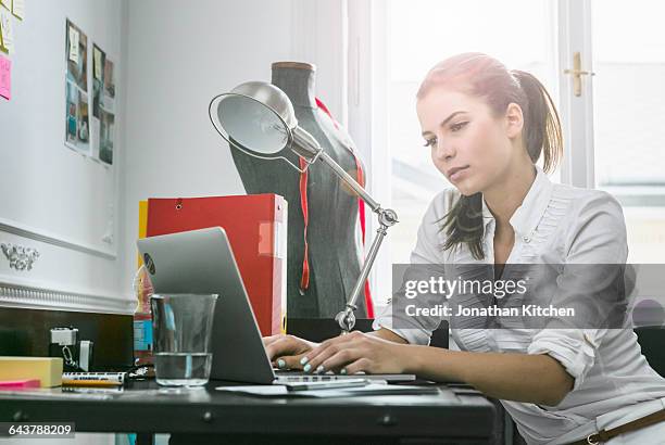 woman sitting at her desk using laptop - creative space stock pictures, royalty-free photos & images
