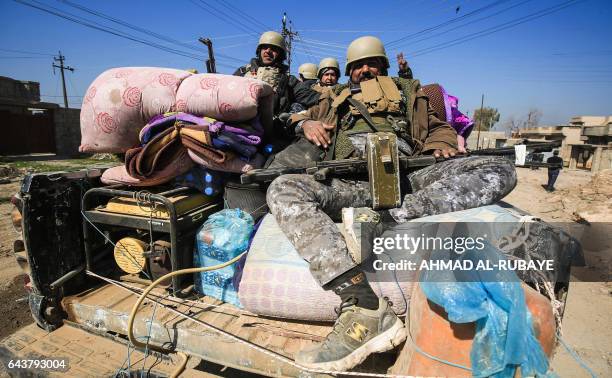 Members of the Iraqi security forces pose from atop an armoured vehicle in the village of al-Buseif, south of Mosul, during an offensive by Iraqi...