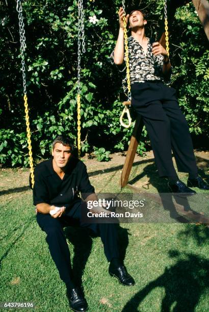 American actor George Clooney and friend, American film and television actor Noah Wyle sit on a swingset circa 1998 in Los Angeles, California.