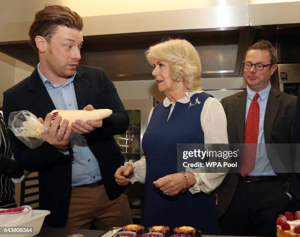 Camilla, Duchess of Cornwall is shown how to use a piping bag by Jamie Oliver alongside Hugh Fearnley-Whittingstall in the kitchen during a reception...