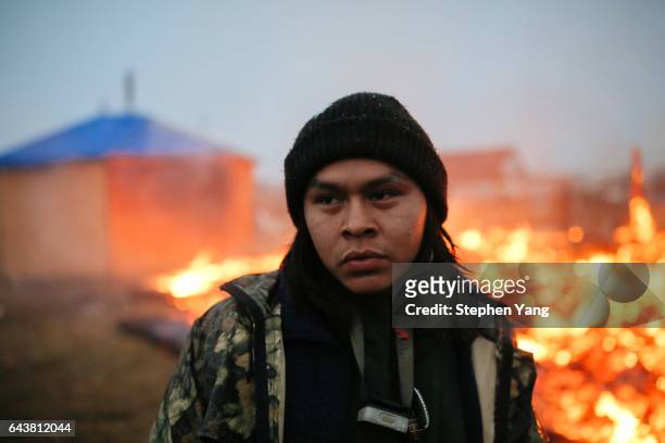 Shea Spencer stands in front of the remains of a hogan structure. Campers set structures on fire in preparation of the Army Corp's 2pm deadline to...