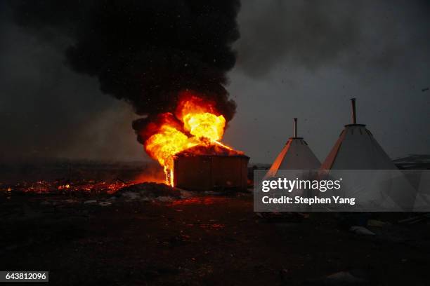 Campers set structures on fire in preparation of the Army Corp's 2pm deadline to leave the Oceti Sakowin protest camp on February 22, 2017 in Cannon...