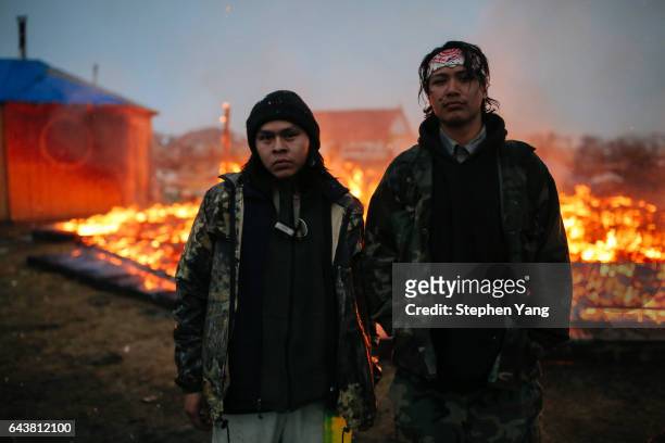 Chanse Zavalla left, and O'Shea Spencer right, stand in front of the remains of a hogan structure. Campers set structures on fire in preparation of...