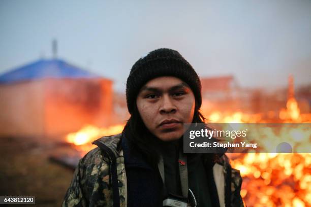 Shea Spencer stands in front of the remains of a hogan structure. Campers set structures on fire in preparation of the Army Corp's 2pm deadline to...