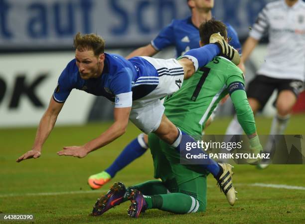 Schalke's defender Benedikt Hoewedes falls over PAOK's goalkeeper Panagiotis Glykos during the UEFA Europa League round of 32 second-leg football...