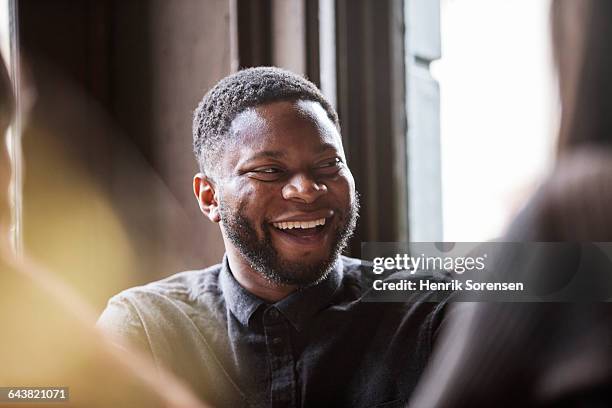man in a pub laughing with friends - low depth of field photos et images de collection