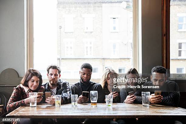 6 friends at a pub with phones - addiction photos et images de collection