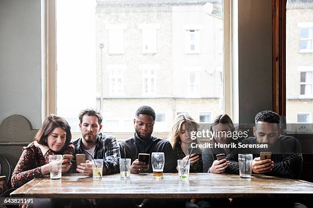 6 friends at a pub with phones - verslaving stockfoto's en -beelden
